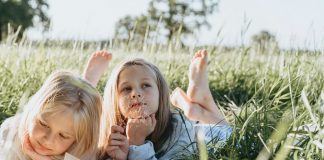 dve-devojčice-čitaju-na-travi