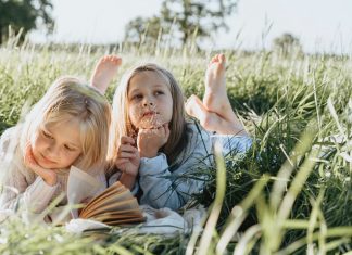 dve-devojčice-čitaju-na-travi
